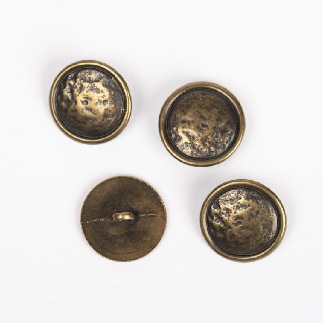 Μεταλλικό κουμπί DROPS Loop Brass 20 mm με ποδαράκι, σε απόχρωση χαλκού. Ανθεκτικό και κομψό, ιδανικό για ζακέτες, παλτό και πλεκτά projects.